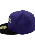 A 2-tone purple and black fitted hat with the San Diego Padres script logo, a 25th Anniversary side patch, and a pink under visor.