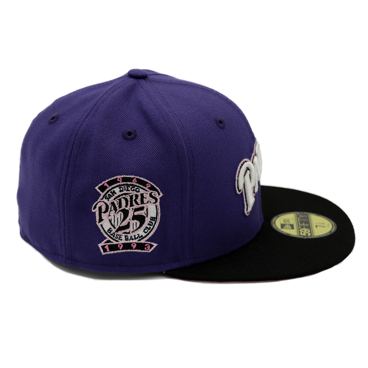 A 2-tone purple and black fitted hat with the San Diego Padres script logo, a 25th Anniversary side patch, and a pink under visor.